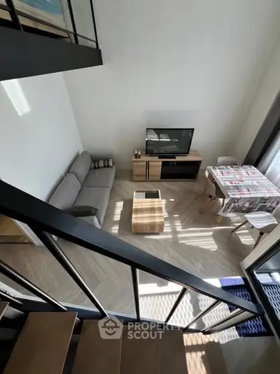 Modern loft-style living room with sleek staircase and cozy furnishings