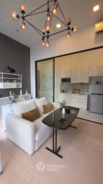 Modern open-layout living room with stylish lighting and sleek kitchen area.