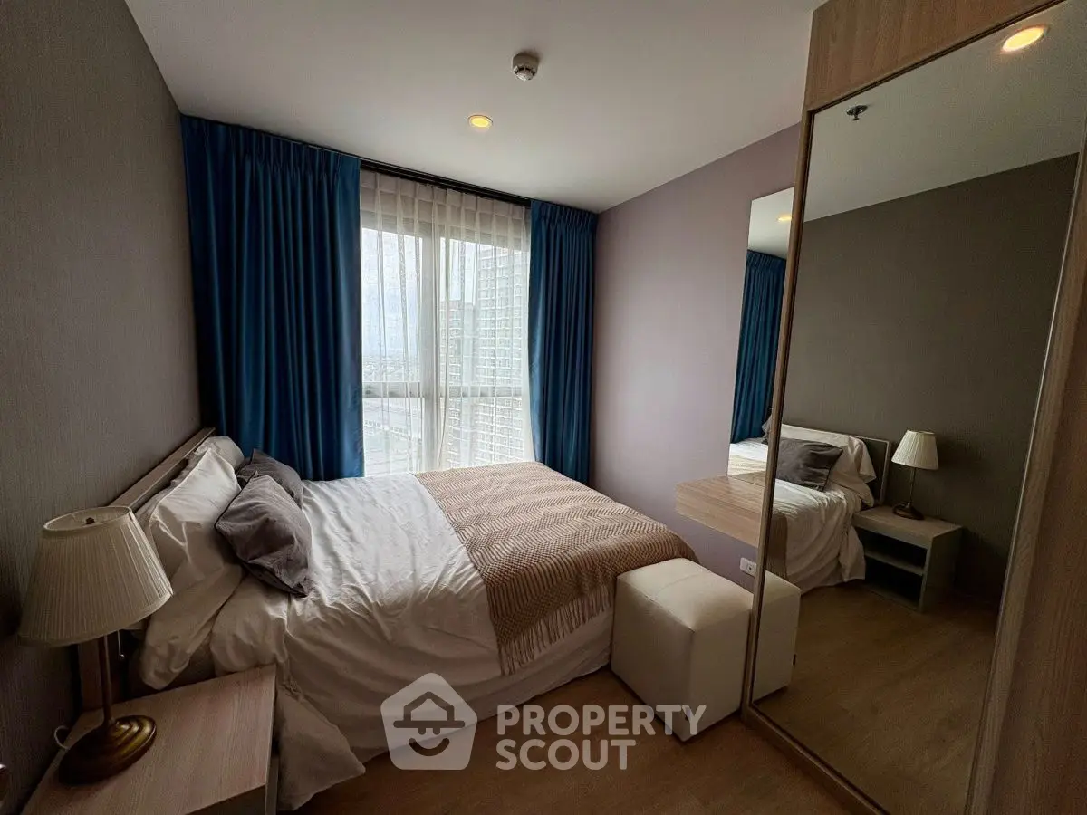 Cozy bedroom with large mirror and city view, perfect for urban living.