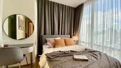 Luxurious bedroom with floor-to-ceiling windows and city view, featuring elegant decor and cozy ambiance.