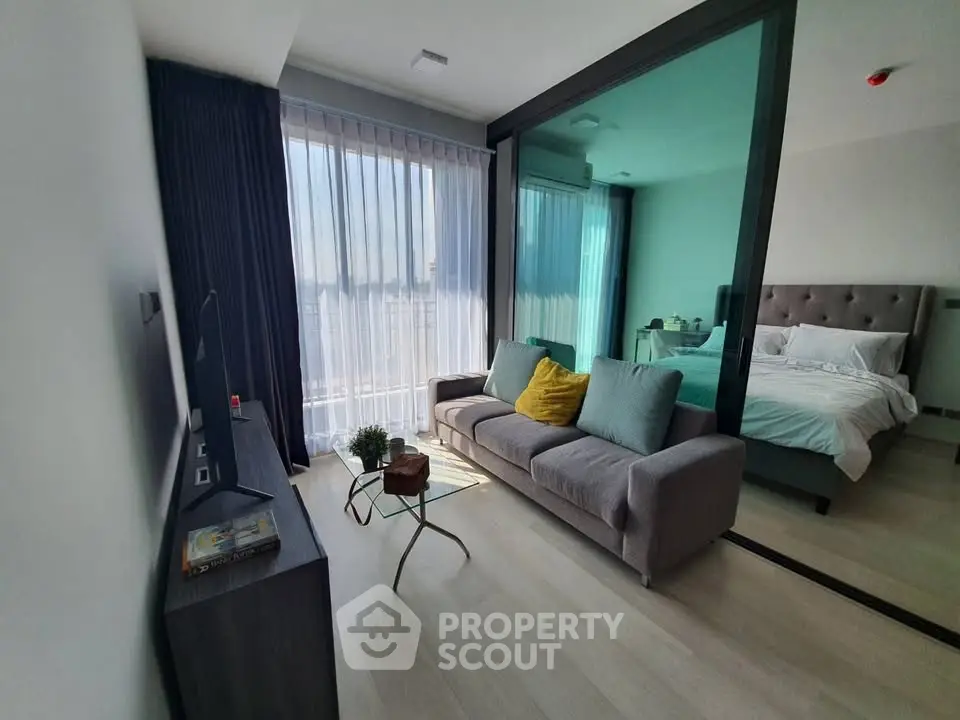 Modern apartment with open living room and bedroom, featuring stylish decor and natural light.