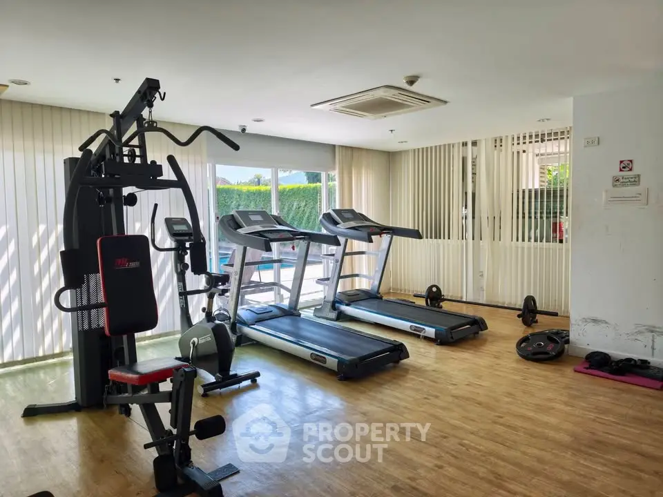 Modern gym with exercise equipment and natural light in a residential building.