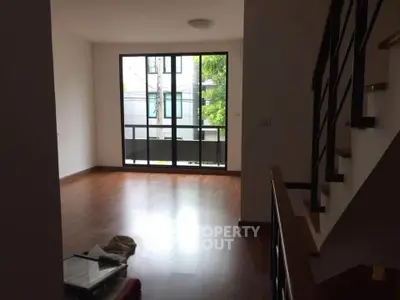 Spacious living room with wooden flooring and large window for natural light.