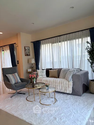 Elegant living room with cozy sofa, stylish armchair, and chic decor in a bright, airy space.