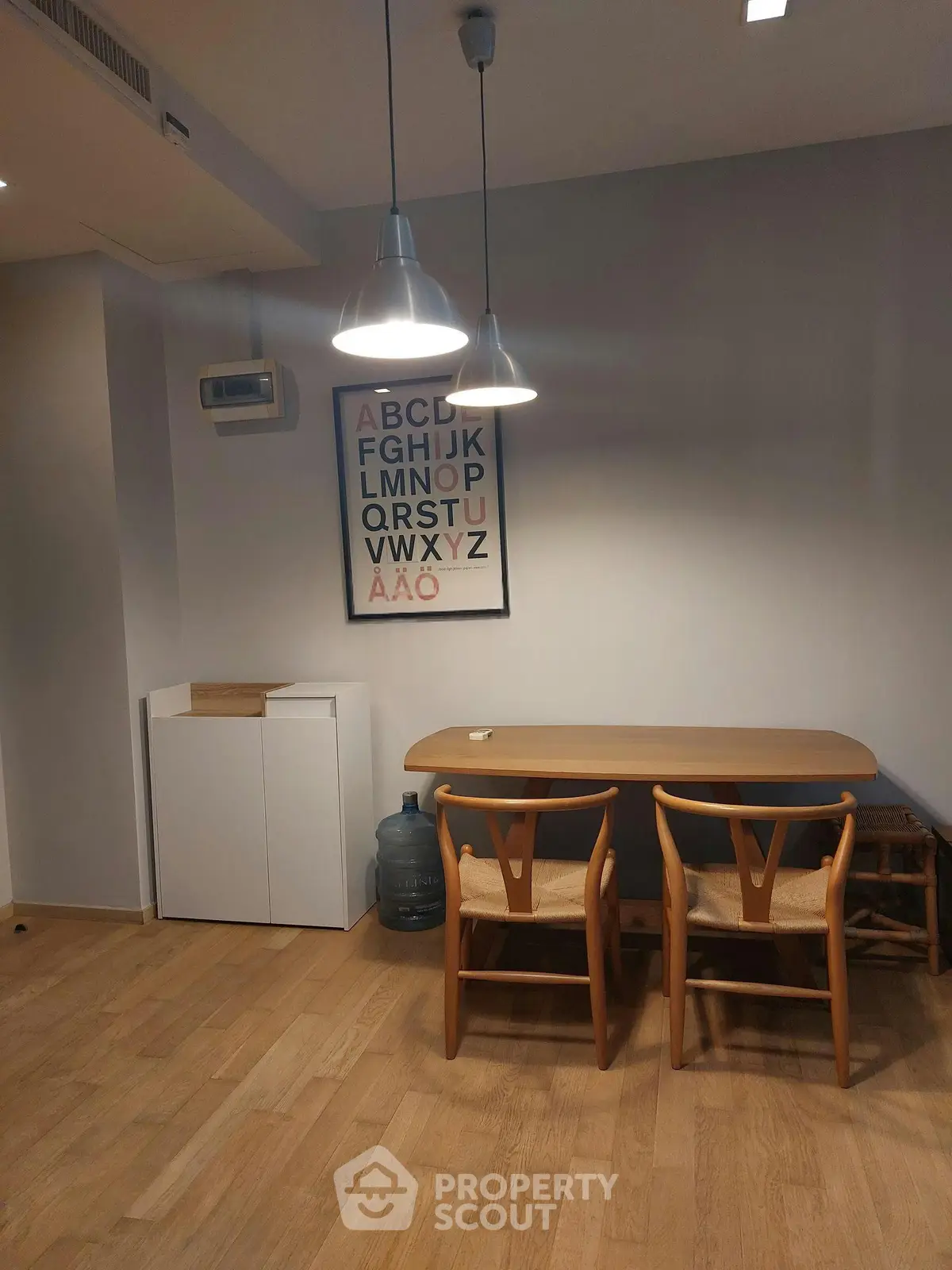 Chic dining area with modern wooden table, stylish chairs, and artistic wall decor in cozy apartment.