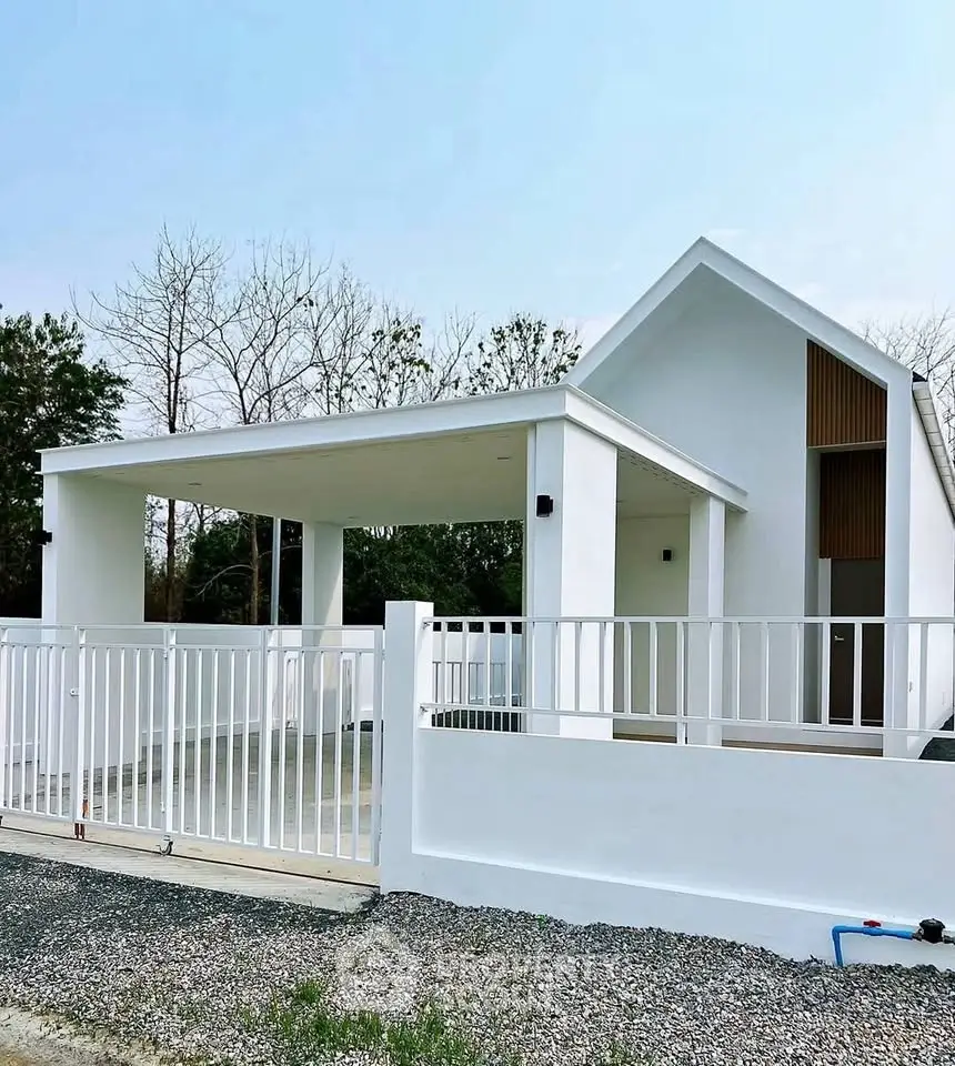 Modern minimalist white house with spacious carport and sleek fence design.