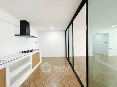 Modern kitchen with sleek design and open layout featuring glass sliding doors and wooden flooring.