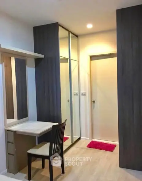Modern study area with sleek desk and chair, mirrored wardrobe, and warm lighting.