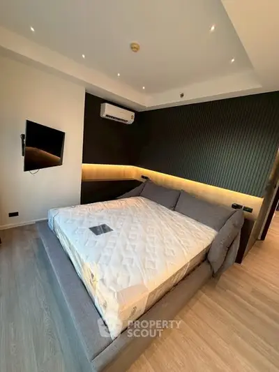 Modern bedroom with stylish lighting and mounted TV, featuring a spacious bed and sleek design.