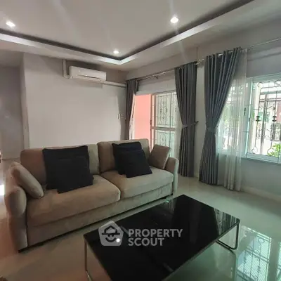 Spacious living room with modern sofa and large windows, perfect for relaxation and entertaining.