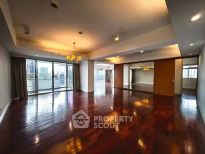 Spacious open-plan living room with hardwood floors and city view balcony.