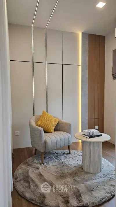 Modern living room with stylish armchair and round rug, featuring elegant wall paneling and ambient lighting.