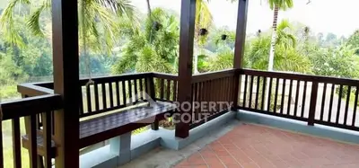 Spacious balcony with wooden railing and lush green view, perfect for relaxation.