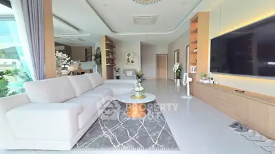 Spacious modern living room with elegant decor and large TV, perfect for relaxation and entertainment.