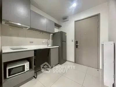 Modern compact kitchen with sleek cabinetry and stainless steel appliances in a stylish apartment.