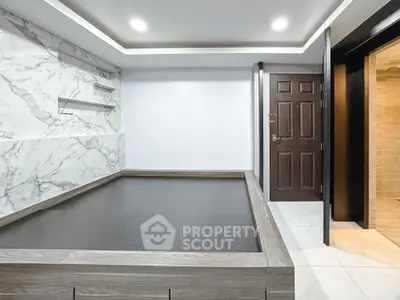 Modern minimalist room with marble accent wall and wooden platform bed