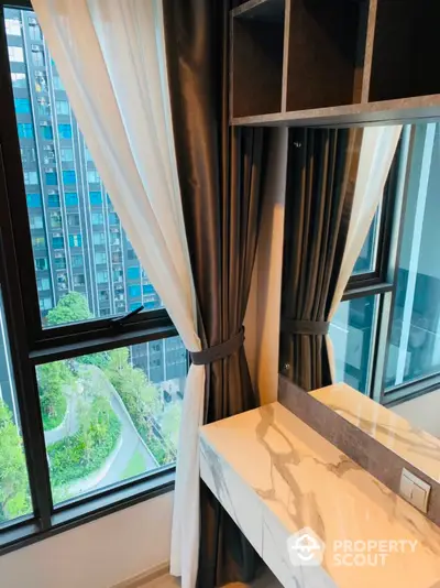 Modern apartment interior with large windows and elegant curtains overlooking cityscape.