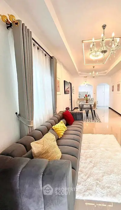 Luxurious living room with plush sofa and elegant dining area, featuring modern chandeliers and stylish decor.