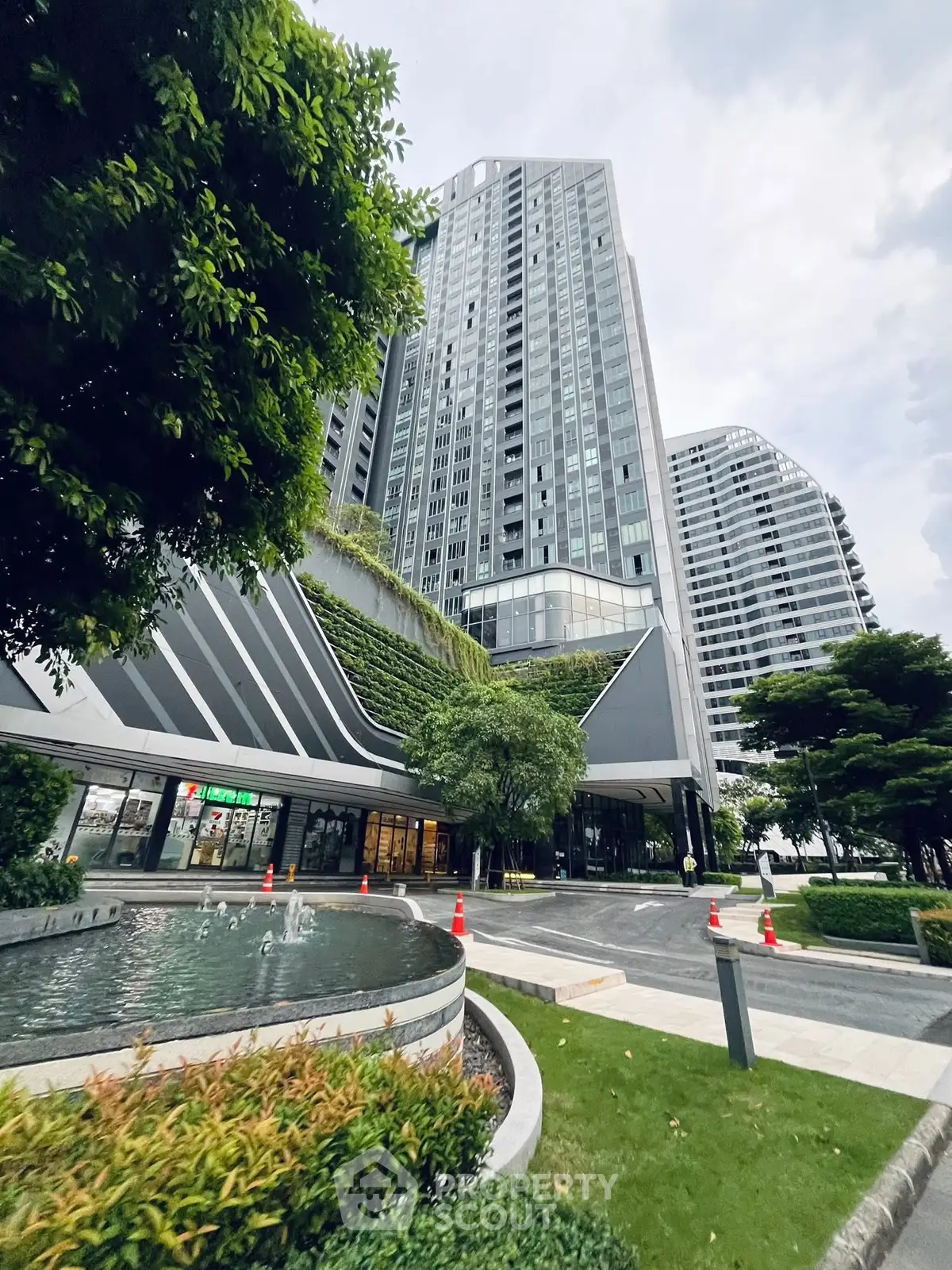 Modern high-rise building with lush greenery and sleek architectural design.