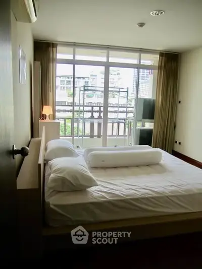 Spacious bedroom with large windows and city view, featuring modern decor and ample natural light.
