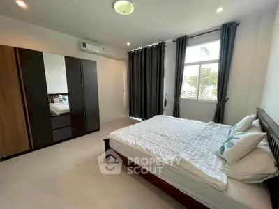 Spacious bedroom with modern decor and large window for natural light