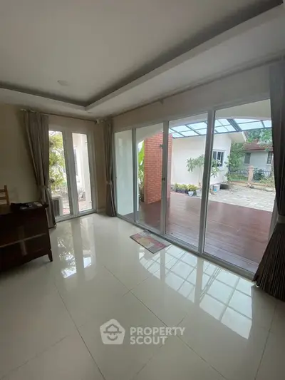 Spacious living room with large glass doors opening to a charming patio area.