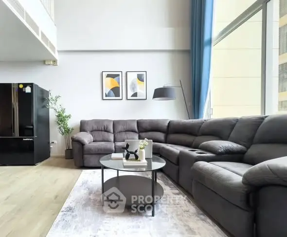 Spacious modern living room with large sectional sofa and stylish decor in a bright apartment.