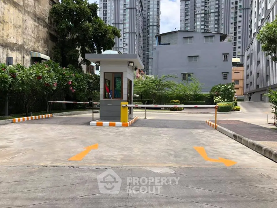 Modern residential building entrance with security booth and lush greenery