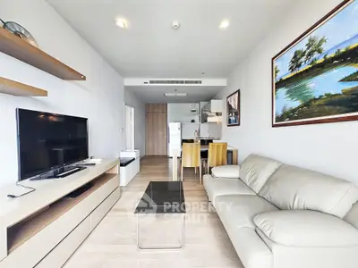 Modern living room with open kitchen, featuring sleek furniture and contemporary decor.