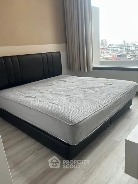 Modern bedroom with large window offering city view and stylish bed frame.