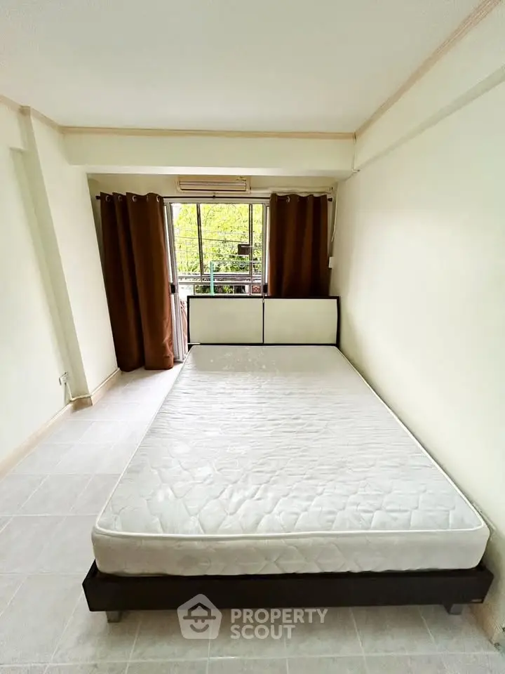 Spacious bedroom with large window and natural light, featuring a minimalist design and neutral tones.