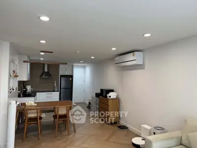 Modern open-plan living room with kitchen, featuring sleek appliances and stylish wooden flooring.