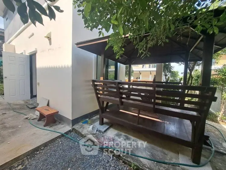 Charming outdoor patio with wooden seating and lush greenery, perfect for relaxation and entertaining.