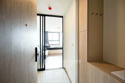 Modern apartment entrance with view into a bright bedroom, featuring sleek design and ample natural light.