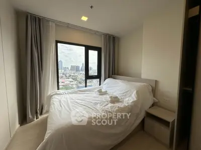 Modern bedroom with city view, featuring a cozy bed and large windows for natural light.