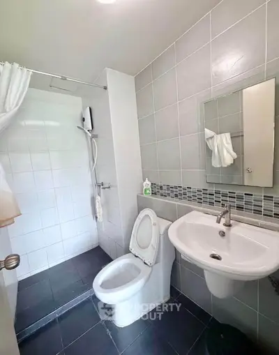 Modern bathroom with sleek fixtures and tiled walls, featuring a shower and toilet.