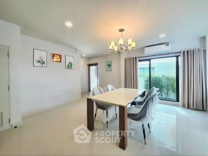 Elegant dining area with modern chandelier and large windows for natural light.