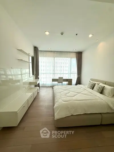 Modern bedroom with large window and stylish decor in a bright apartment.