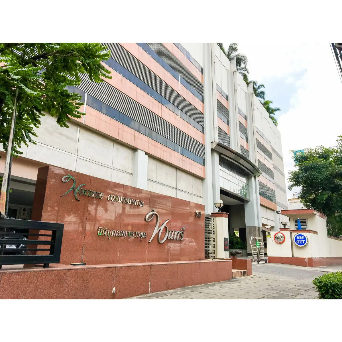 Modern condominium entrance with stylish facade and lush greenery, perfect urban living.