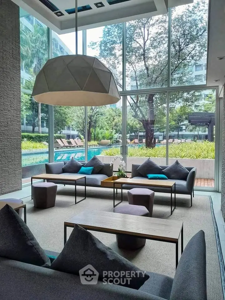 Luxurious modern living room with floor-to-ceiling windows overlooking a serene pool and lush garden.