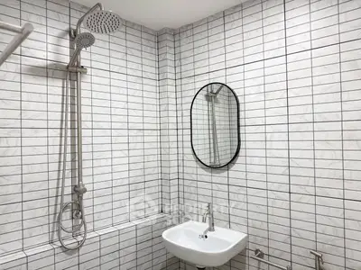 Modern bathroom with sleek shower and stylish oval mirror, featuring contemporary white tile design.