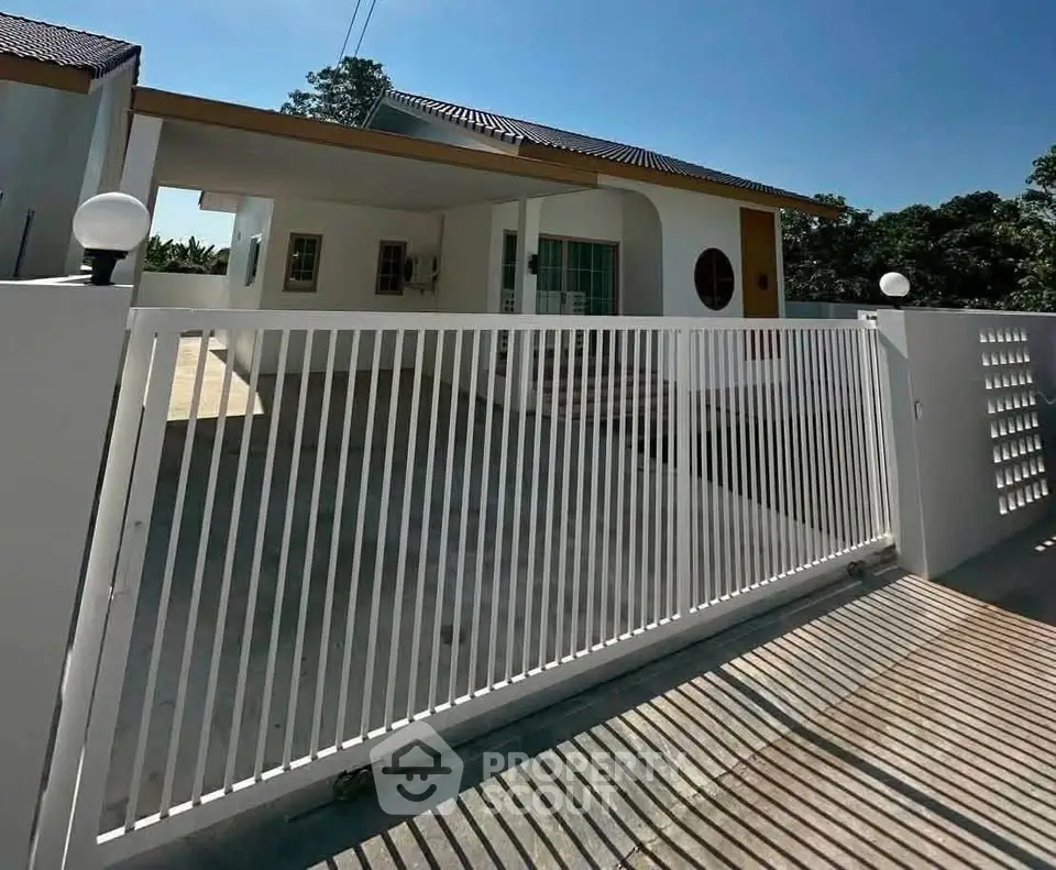Modern single-story house with gated driveway and carport in a serene neighborhood.