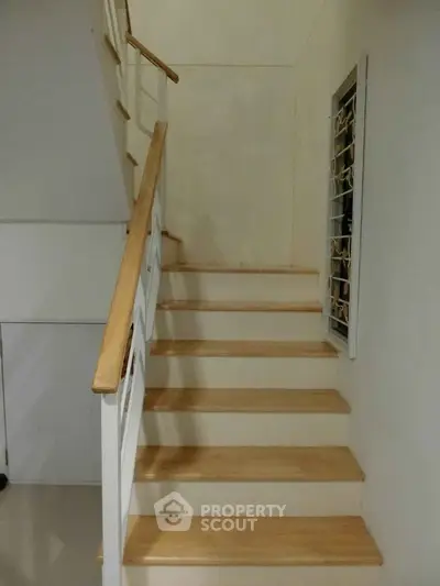 Modern staircase with wooden steps and white railing in a contemporary home