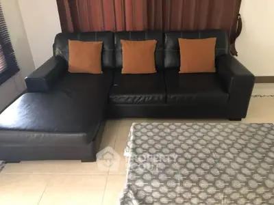 Spacious living room with stylish black leather sectional sofa and elegant decor.
