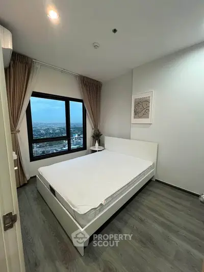Modern bedroom with large window offering stunning city view, featuring minimalist decor and cozy ambiance.