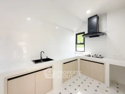 Modern kitchen with sleek white cabinets and gas stove, featuring elegant tile flooring and ample natural light.