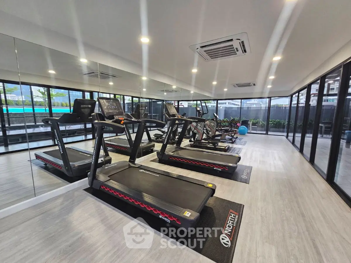 Modern gym with treadmills and large windows in luxury apartment complex.