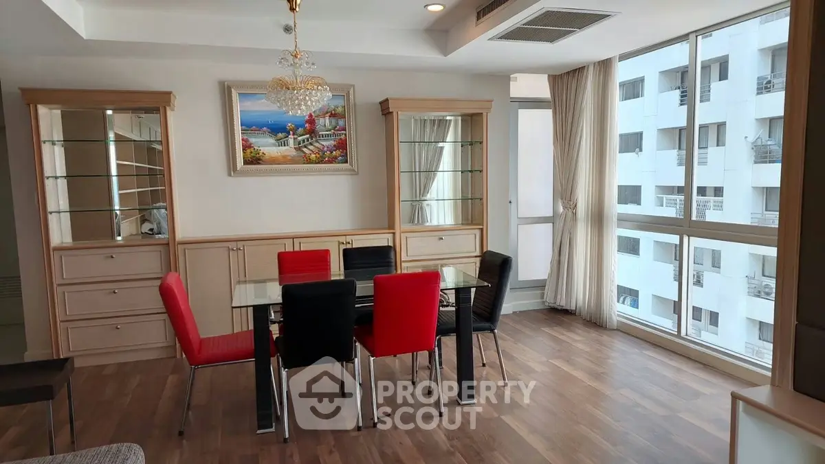 Elegant dining room with glass table and vibrant chairs in a modern apartment with city view.
