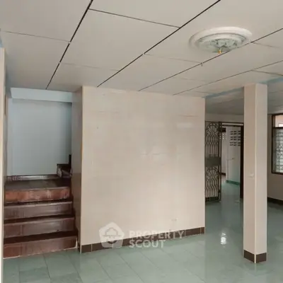 Spacious interior with tiled floors and staircase, ideal for customization.