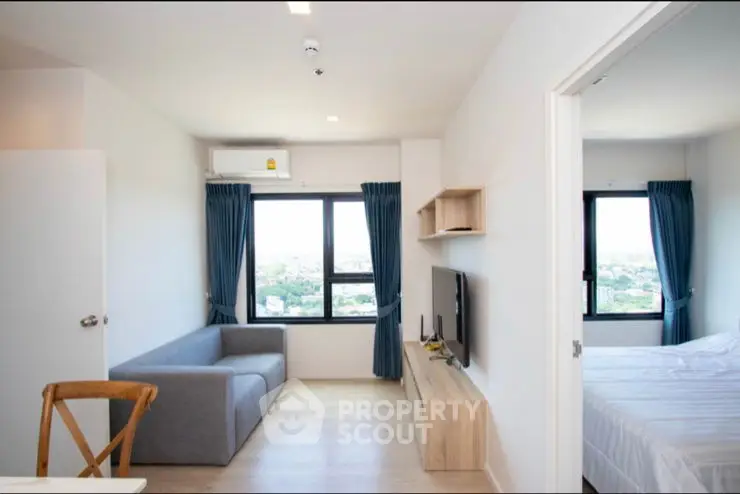 Modern apartment with open living room and bedroom, featuring large windows and stylish decor.